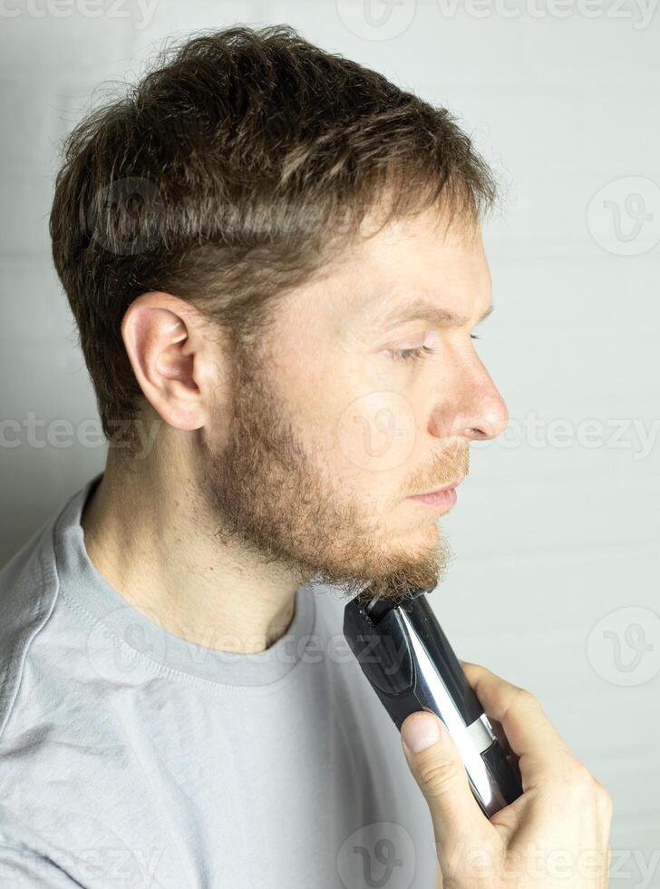 a man trims his beard with a trimmer. An electric razor trimming a beard. photo
