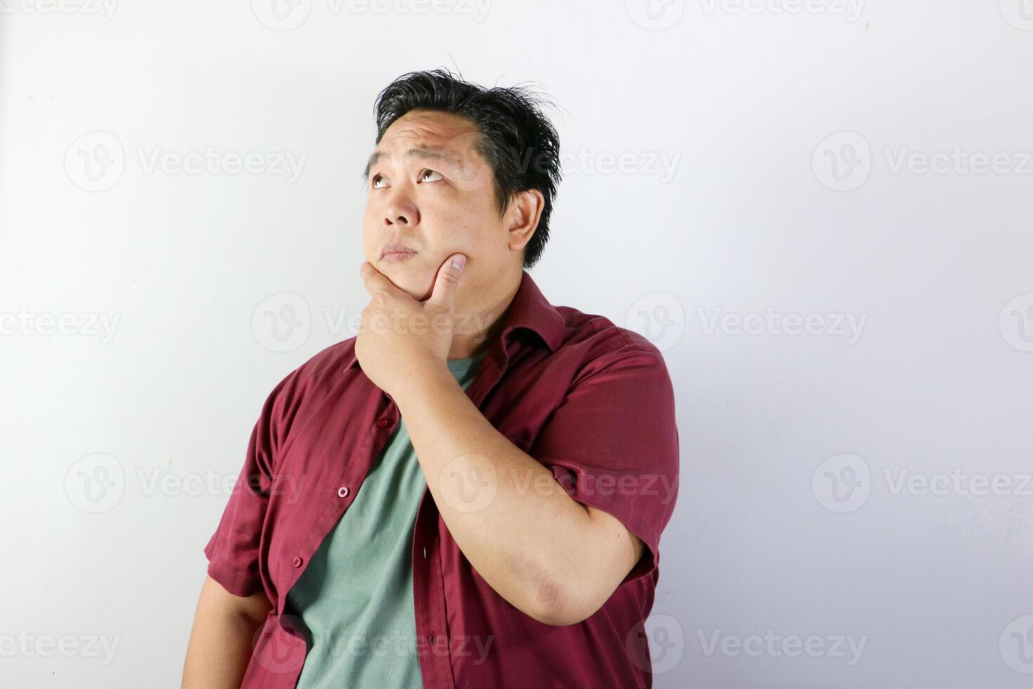 Thoughtful Asian man holding his chin and thinking with serious expression consider something photo