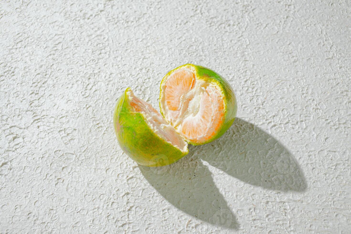 a green orange gradient citrus fruit isolated on a textured white background, showcasing its vibrant color transition photo