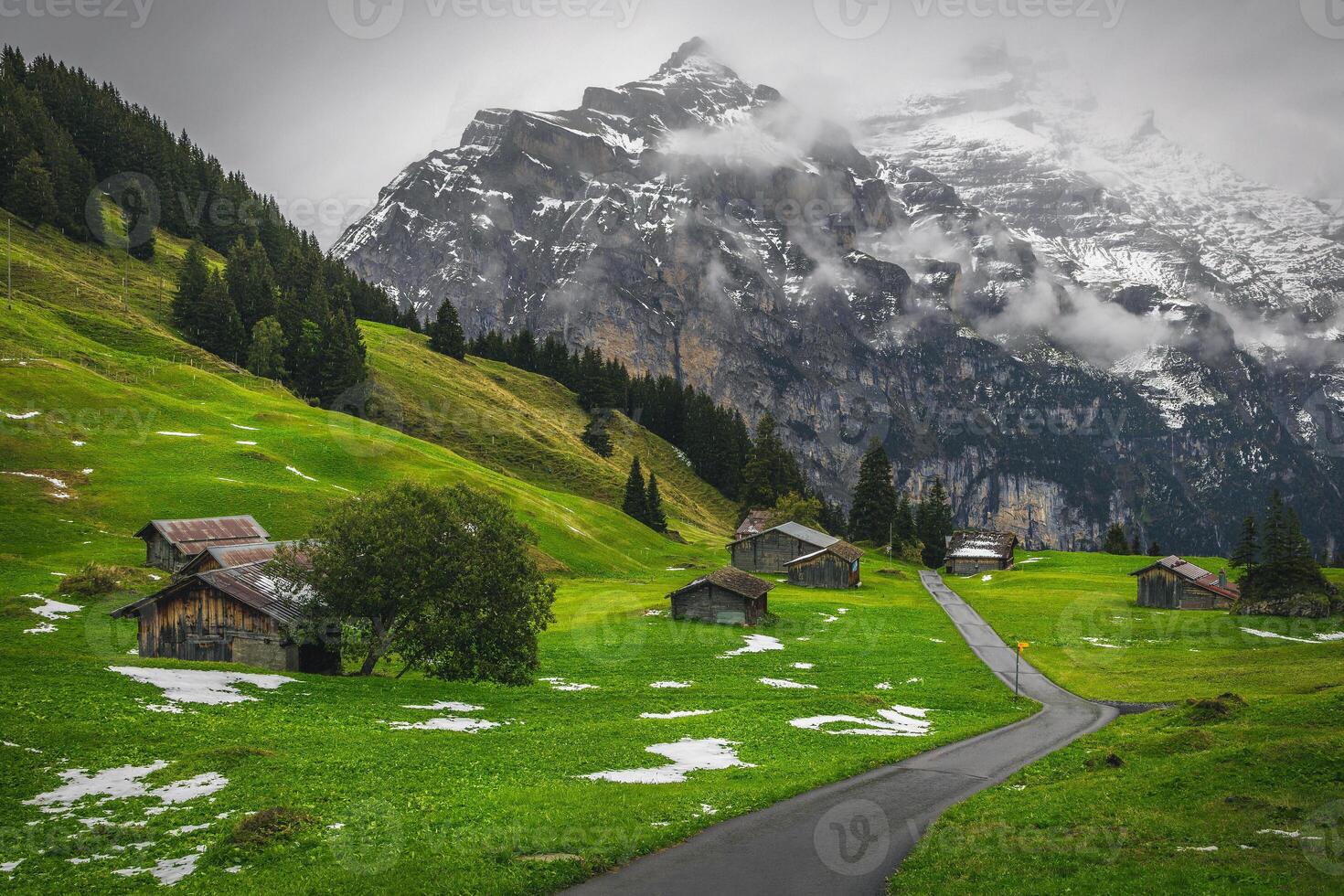 Scattered alpine wooden huts and misty snowy mountains in Switzerland photo