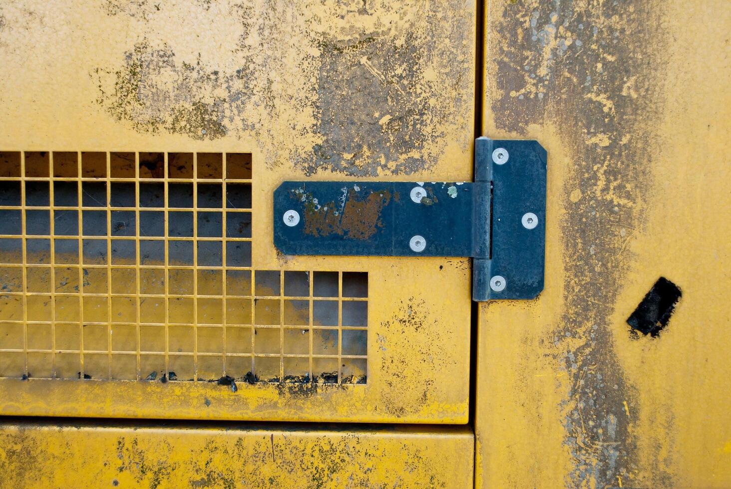 Black hinge on old yellow steel wall photo