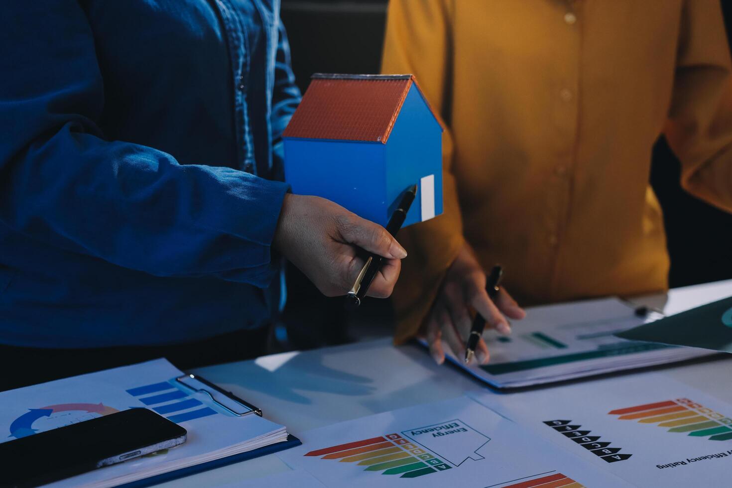 Two people holding a house model and a paper with graphs photo