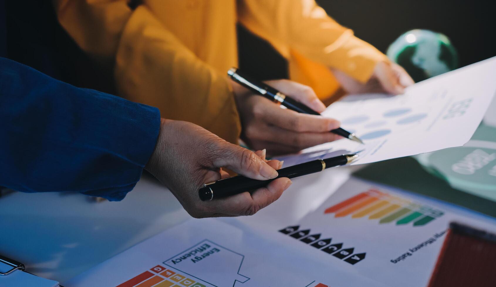 Two people are holding a pen and paper while looking at graphs photo