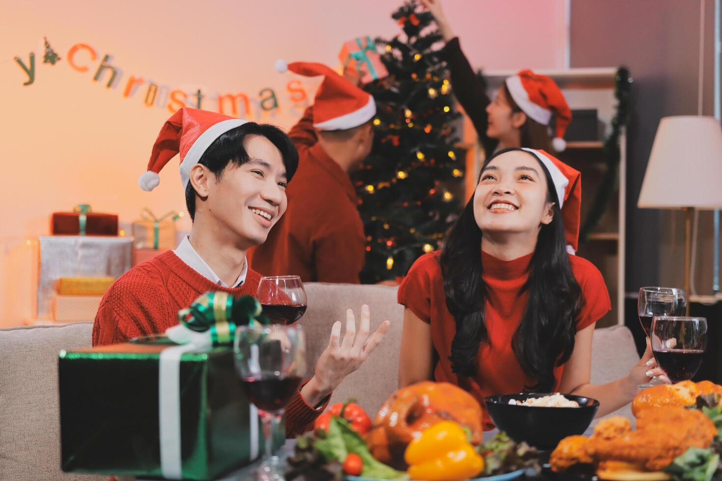 A couple in christmas clothes sitting at a table with wine and food photo