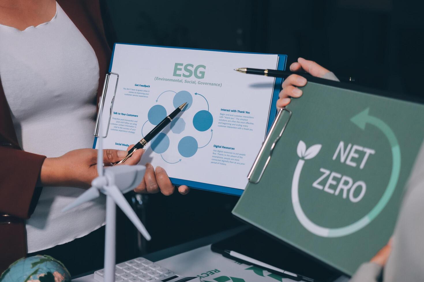 Two people holding up a folder with the word net zero on it photo