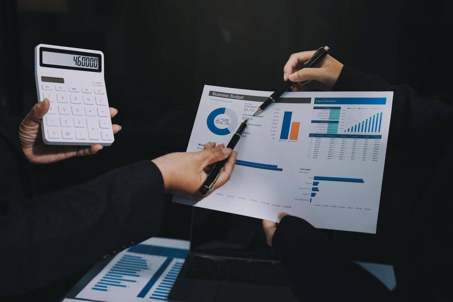 Business people holding a calculator and papers with graphs photo