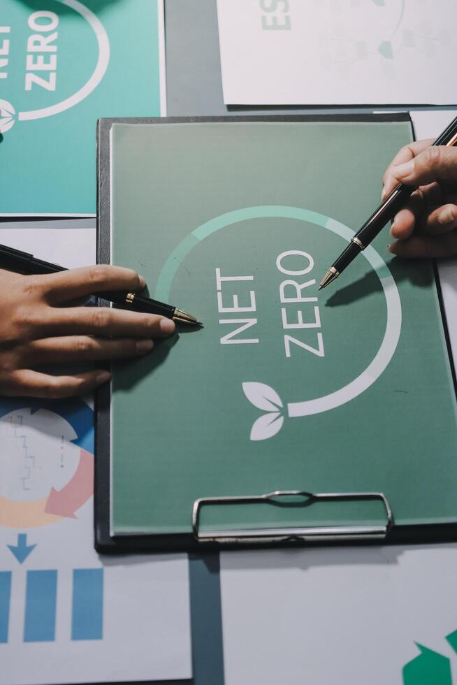Two people are working on a green board with the word net zero photo