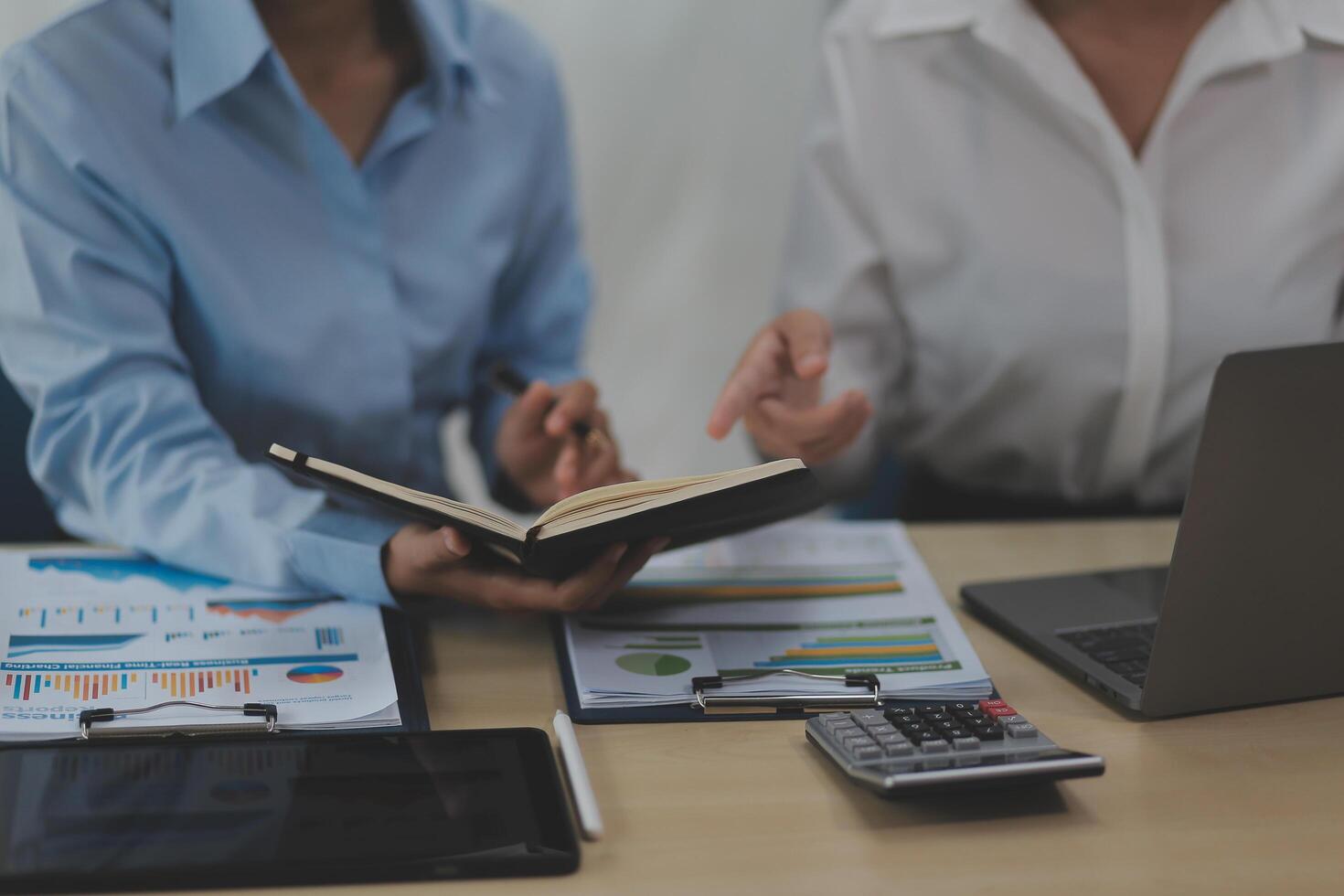 Two business people sitting at a table with a laptop and a book photo