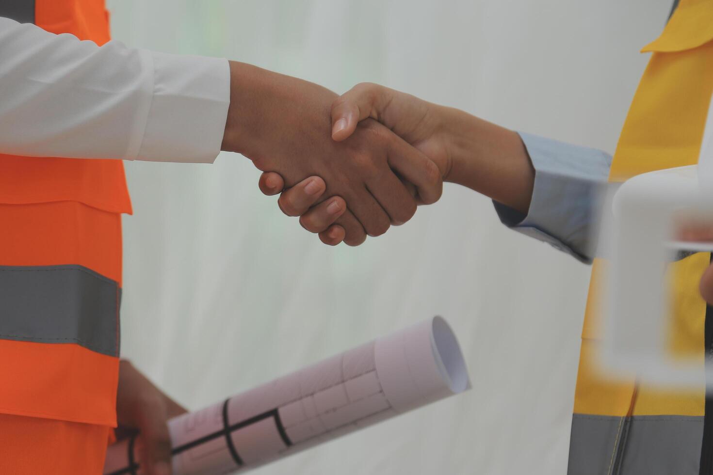 Two people shaking hands while holding construction plans photo