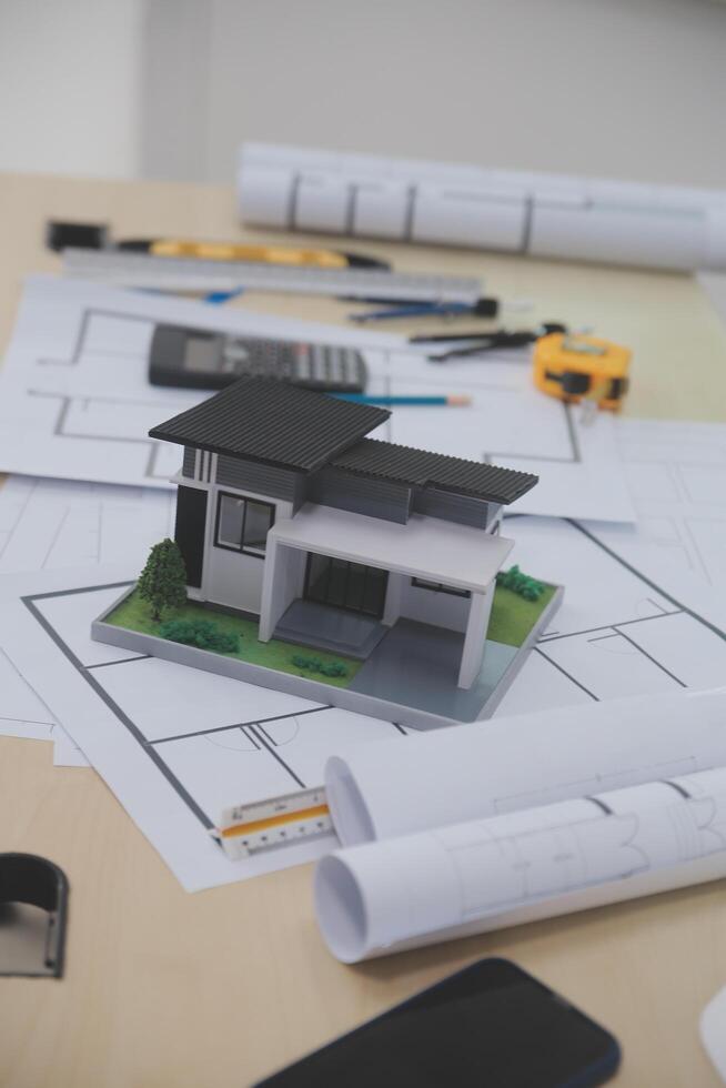 A table with a house model, construction plans and other items photo