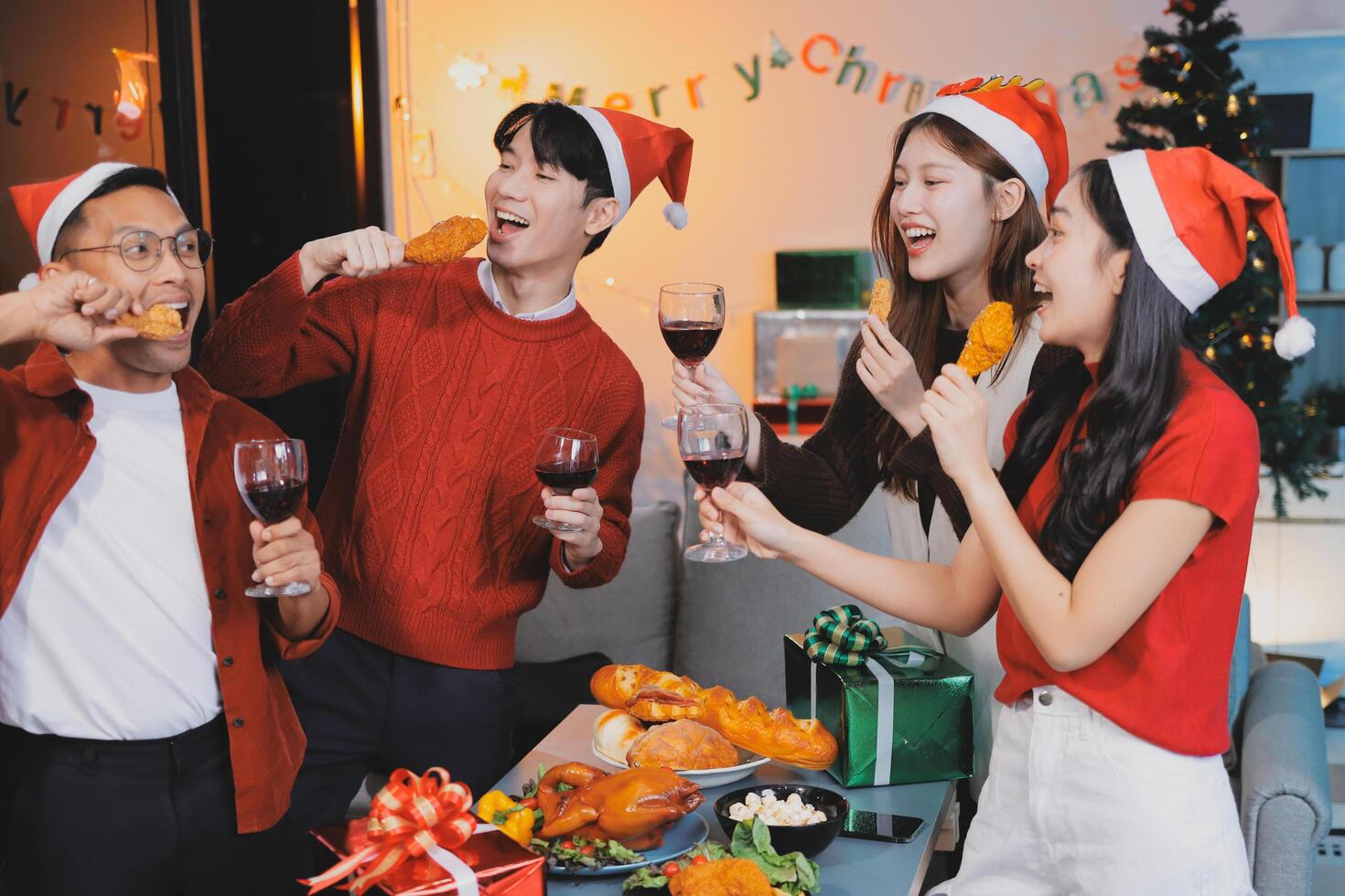 Four people wearing santa hats and drinking wine photo