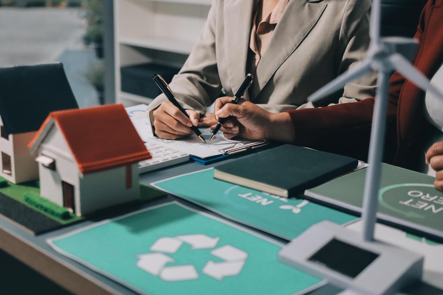 Two business people working on a project with a house and wind turbines photo