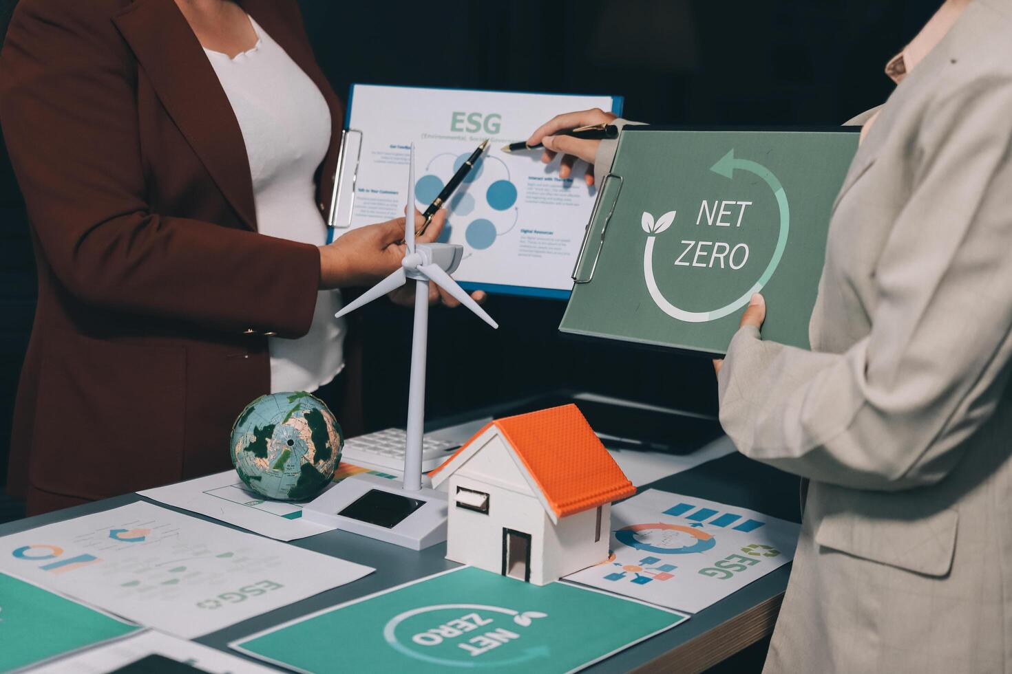 Two people standing around a table with net zero signs photo