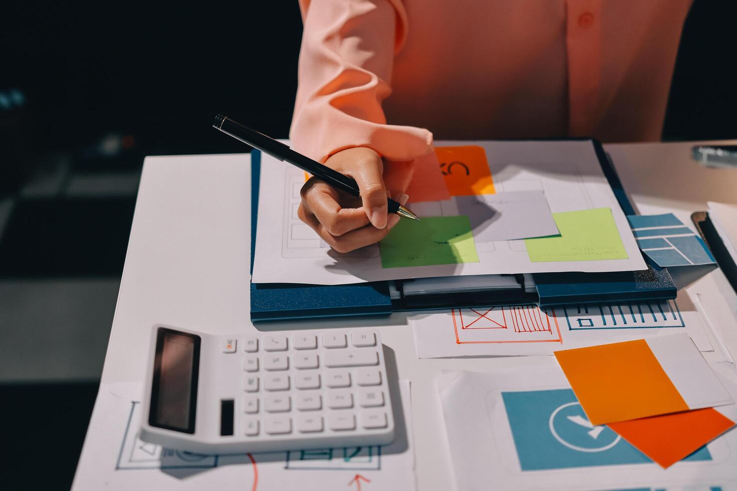 A person is writing on a piece of paper with a calculator photo