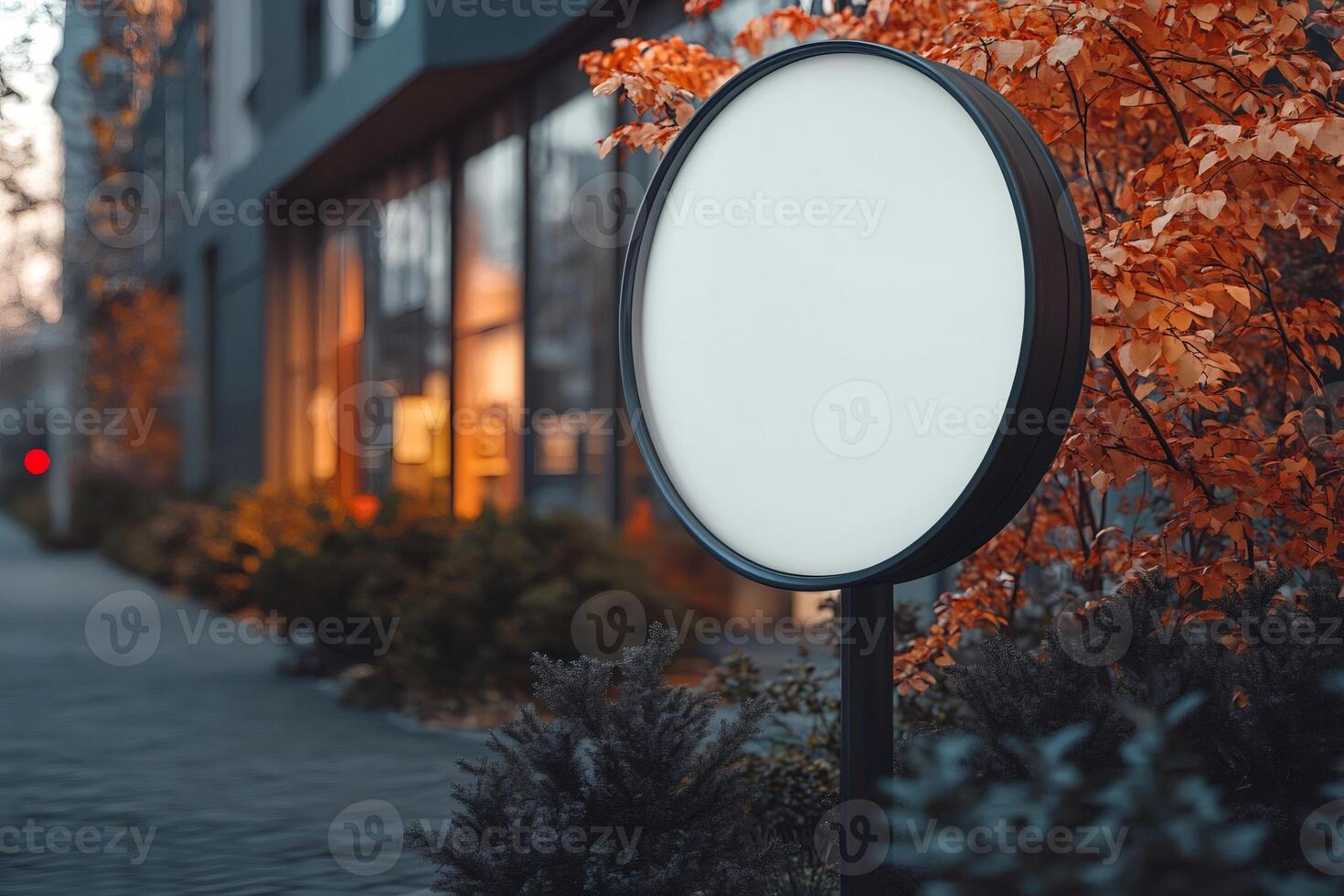 Round signage mockup standing next to a modern building with autumnal trees photo
