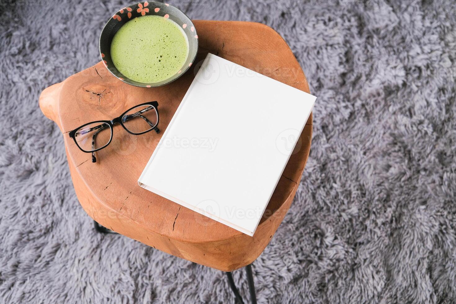 blank book cover mockup on coffee table with green matcha tea, gray fluffy rug on the floor, copy space photo