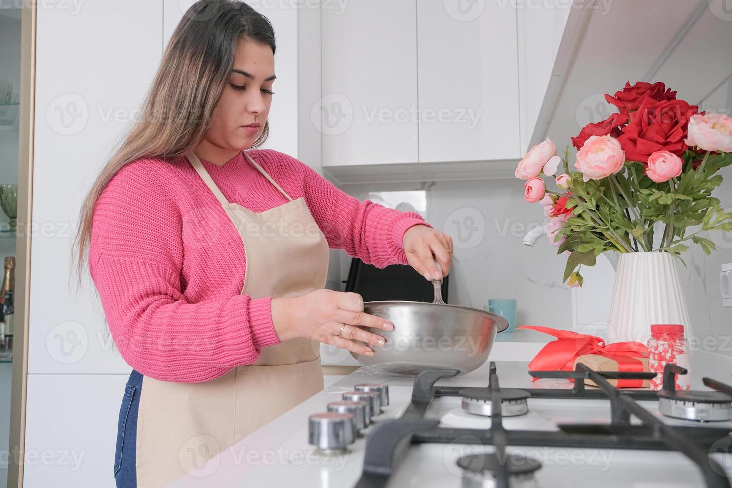 brunette woman cooking in the kitchen, mixing cookies dough photo