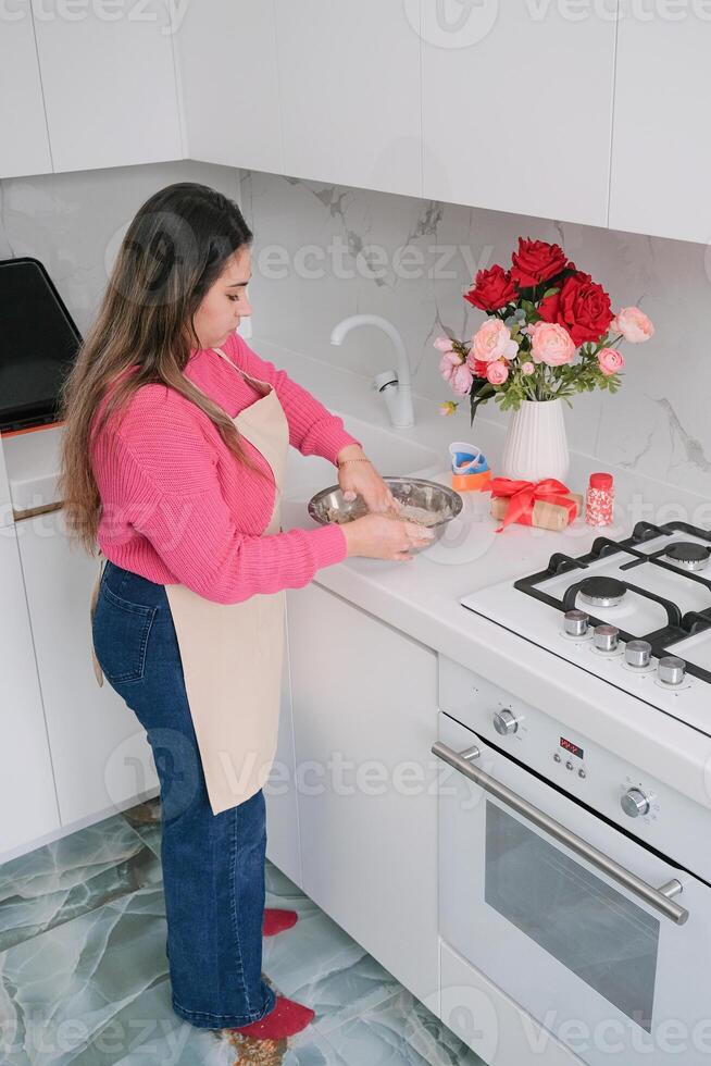 brunette woman cooking in the kitchen, beautiful red and pink flower bouquet photo