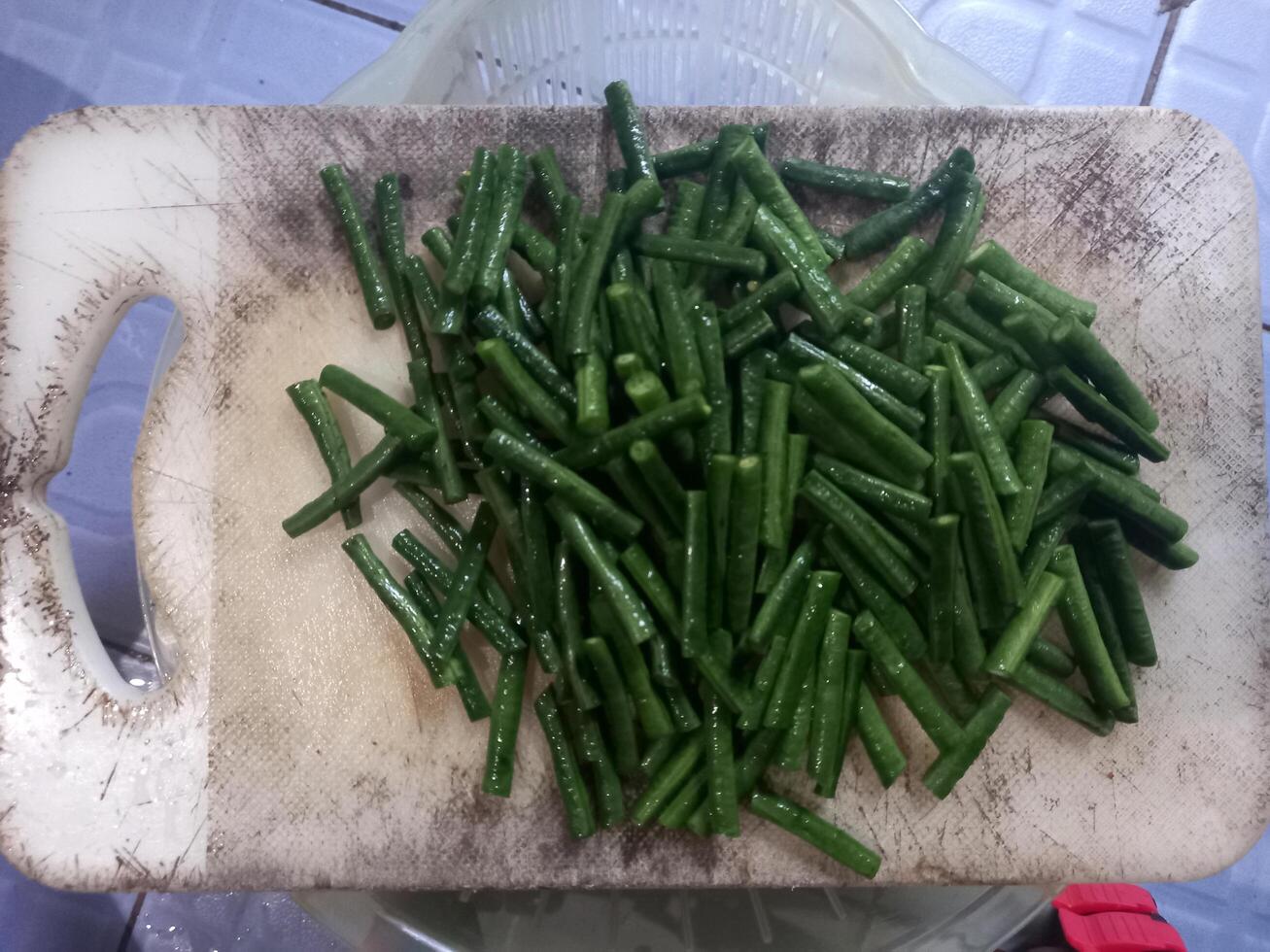 long beans that have been cut into small pieces on a chopping board photo