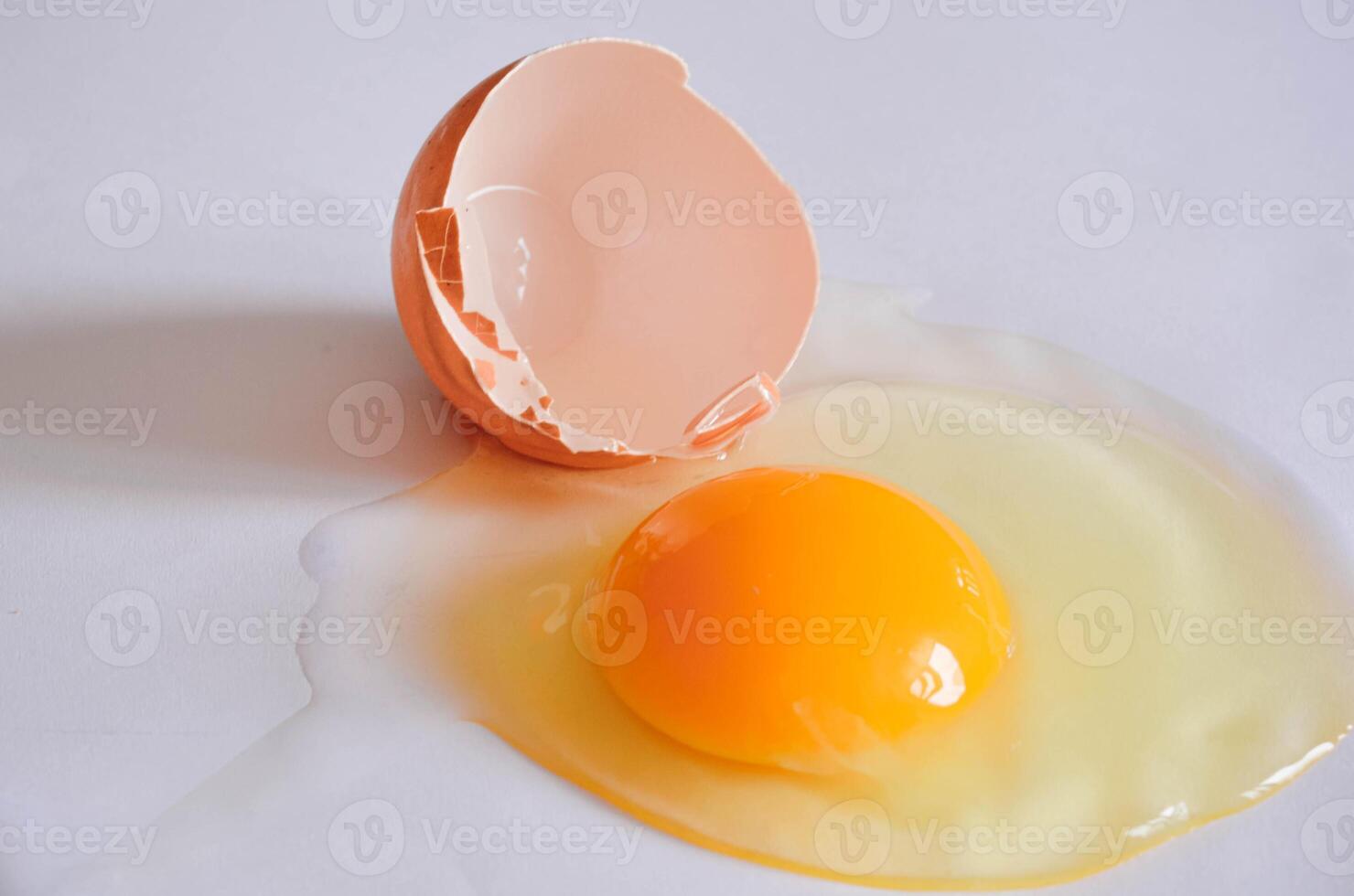 Cracked Egg with Yolk and Shell on White Background marco shot photo