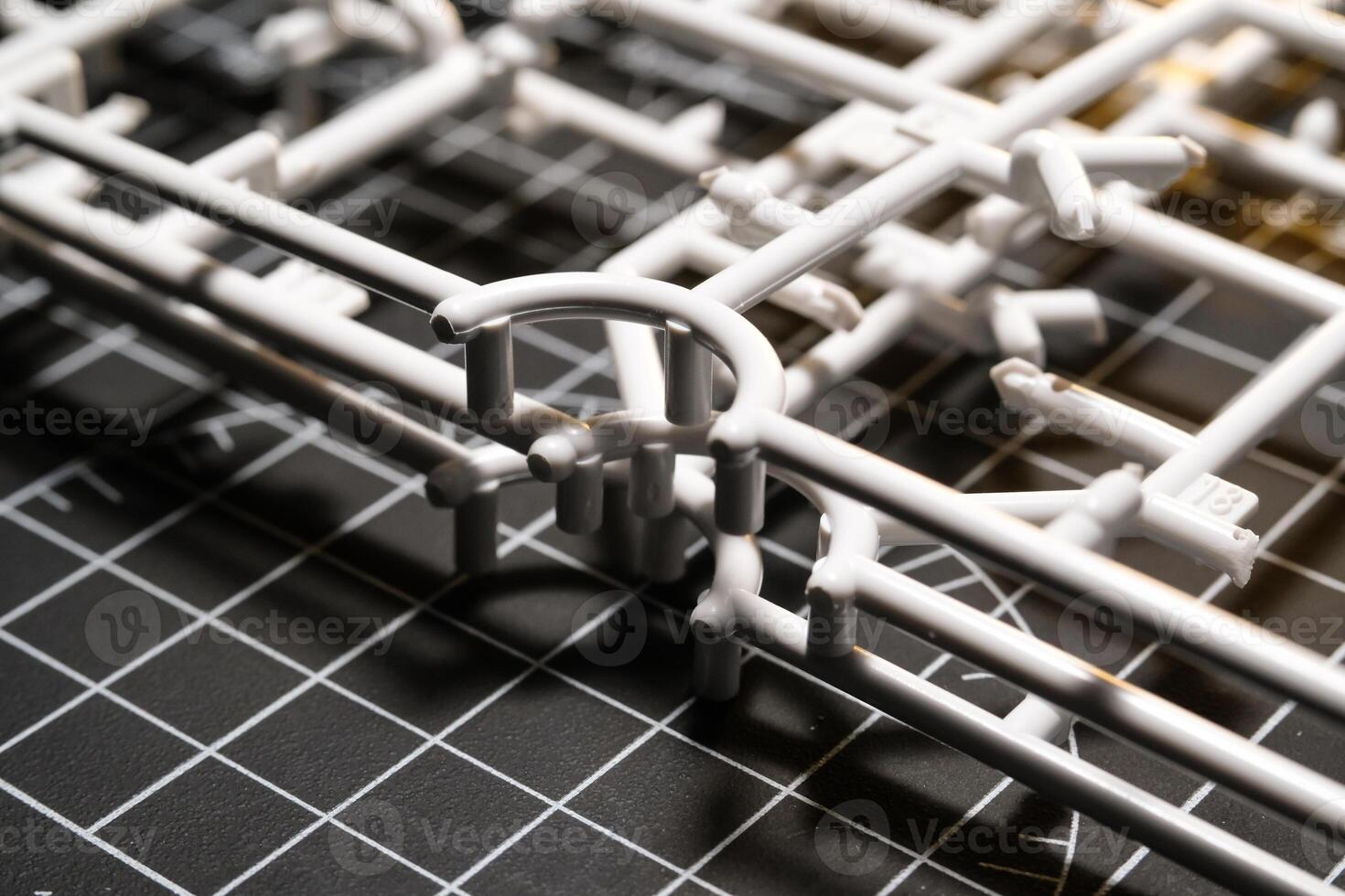 Stack of white Plastic Frames on Black rubber cutting mat. Abstract Backgrounds of model kit frames. Part of plastic model kit and tools for building robot. Miniature, Frame, Plastic, Object photo