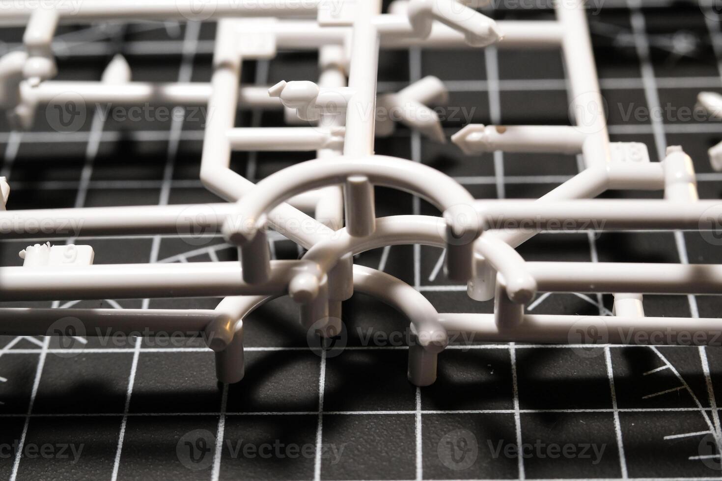 White Plastic Frames on Black rubber cutting mat. Abstract Backgrounds of model kit frames. Part of plastic model kit and tools for building robot. Miniature, Frame, Plastic, Object photo
