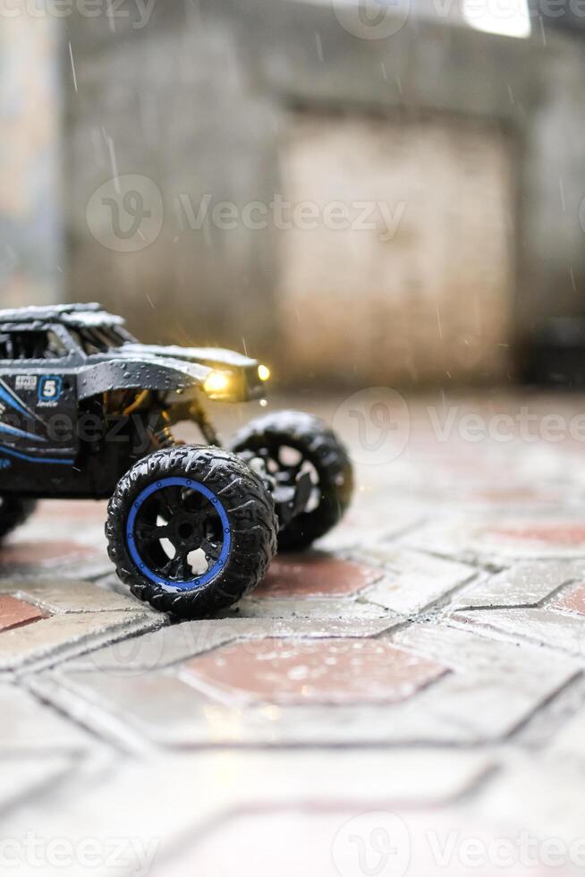 Toy car during outdoor rain with lights on. Remote Control Car being played in the yard during rain. Hobbies and Leisures. Graphic Resources. Toy Photography photo