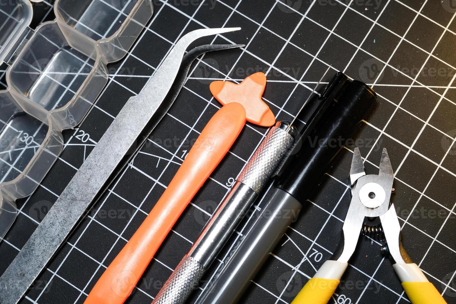 Set of hobby tools for building plastic model kits. Consisting of Nipper, Ink pen, cutting blade, plastic separator, tweezer, and transparent plastic container. Tools and equipments on black photo