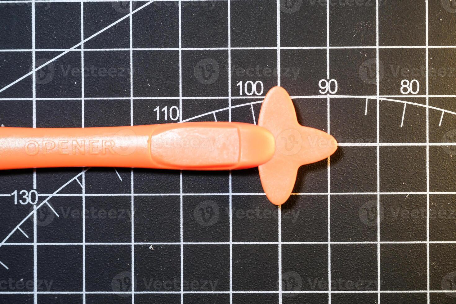 Closeup Plastic opener on black striped rubber mat. Plastic opener is used to remove and disassemble model kits parts that have been installed. Plastic tools and equipment for hobbyists. photo