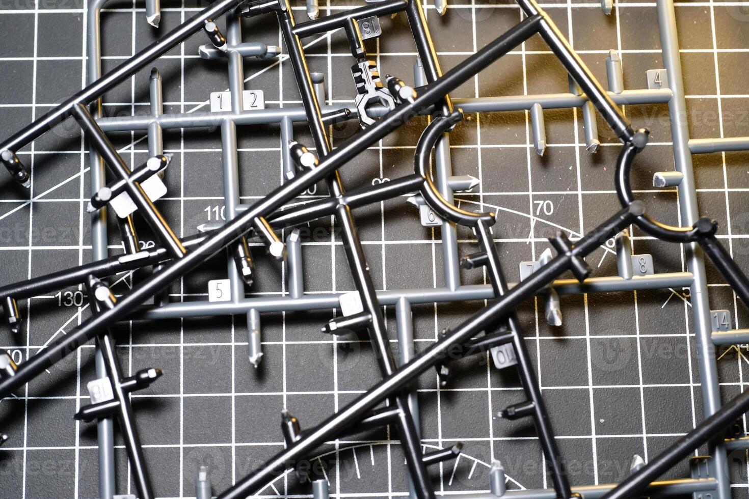 Abstract Backgrounds of Black Plastic Frame for Model Kit. Plastic model kit frame with black cutting mat background with striped pattern. Building Robot Model Kit. Toys and Hobbies photo