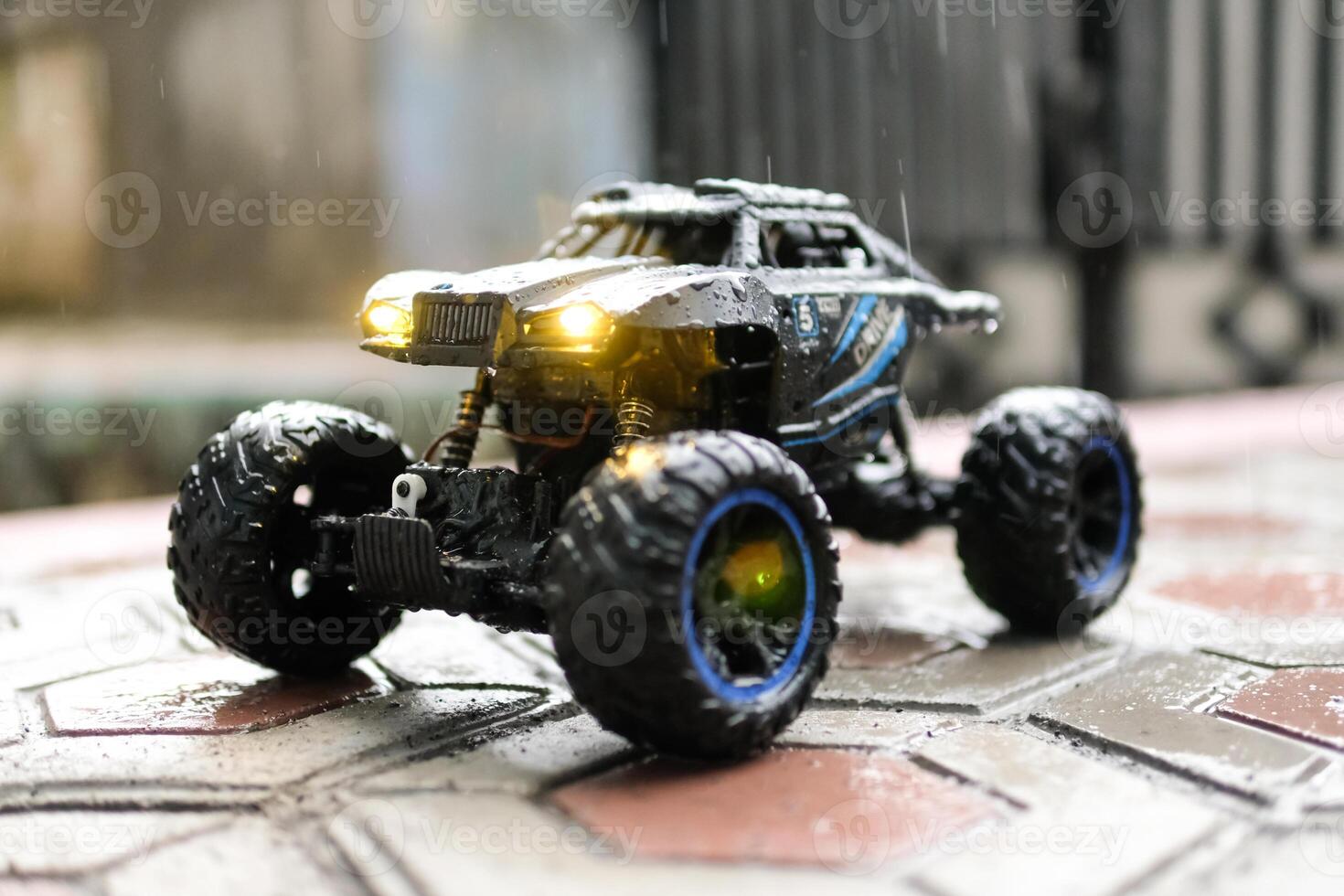 Toy car outdoor rain with lights on. Remote Control Car being played in the yard during rain. Hobbies and Leisures. Graphic Resources. Toy Photography Concepts photo