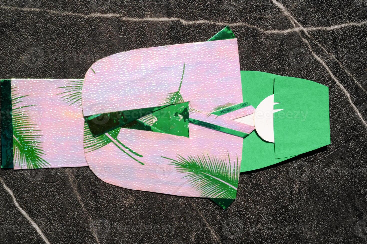 Origami in the shape of a woman in a kimono. Green paper is used for hair and pink paper is used for kimono clothes. The art of paper folding. Origami craft isolated in black background photo