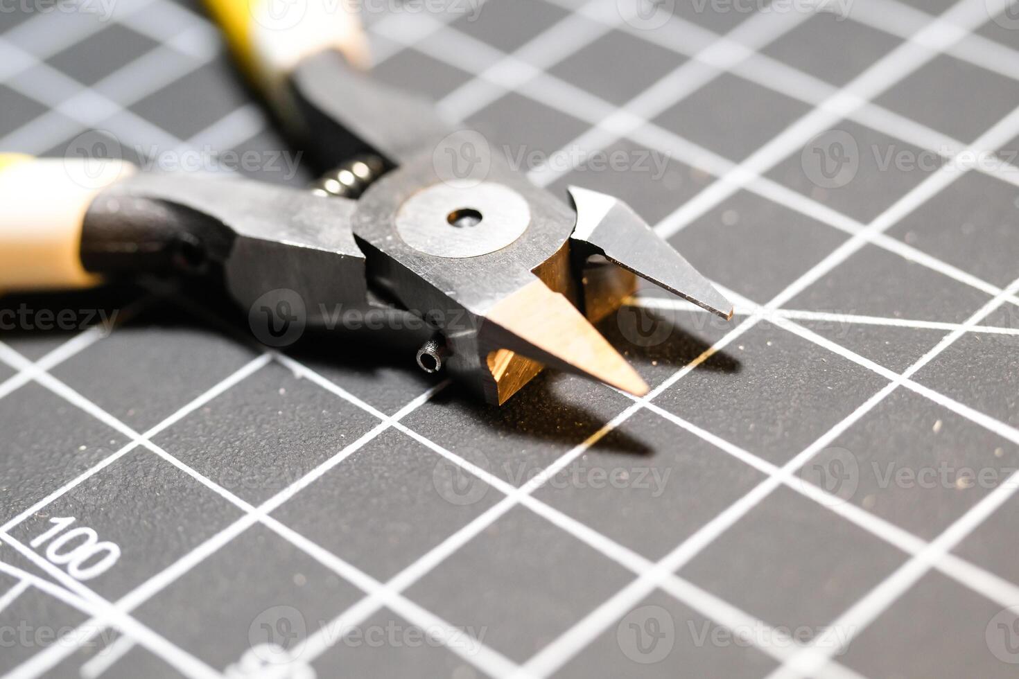 Closeup single blade nipper tools on black cutting mat. Nippers are used to cut small plastic parts. Pliers are used to cut. Model kit builder tools. Hobbies and leisures. photo