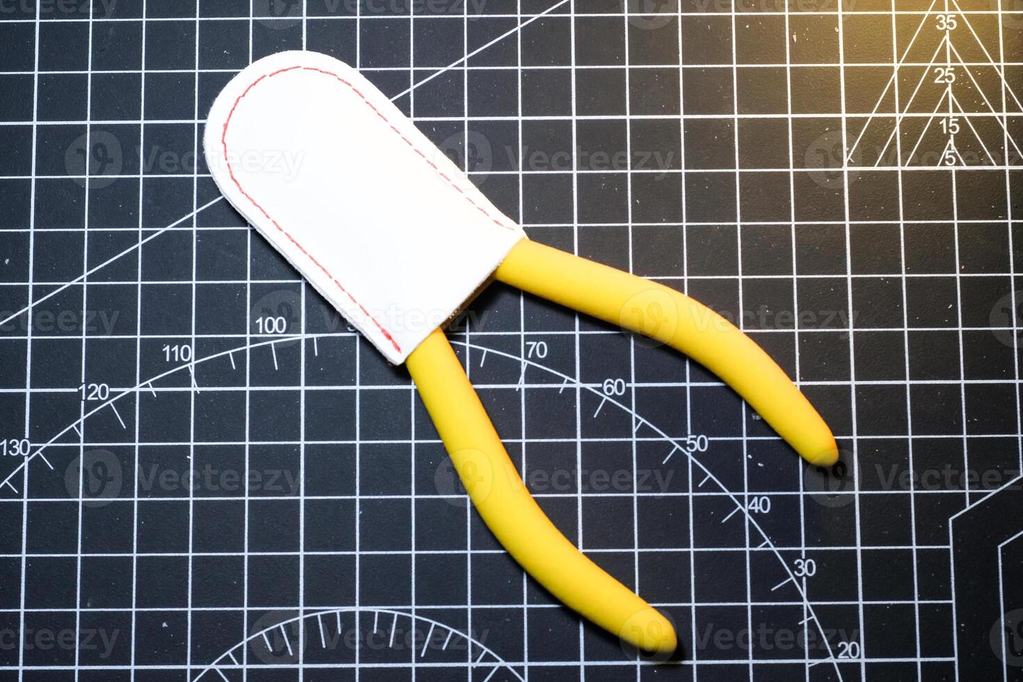Yellow Nipper and white cap on black striped rubber cutting mat. Single blade nipper functions to cut plastic model kit parts. Metal tools for robot model kit hobbyists. Negative Space photo