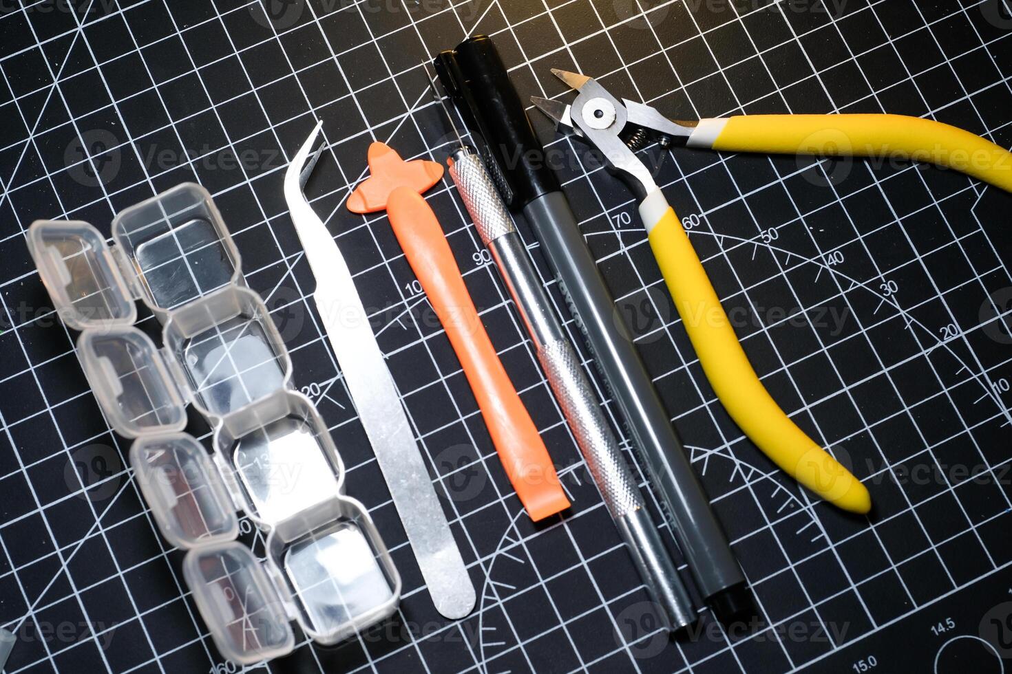 Set of tools for building plastic model kits. Consisting of Nipper, Ink pen, cutting blade, plastic separator, tweezer, and transparent plastic container. Tools and equipments on black photo