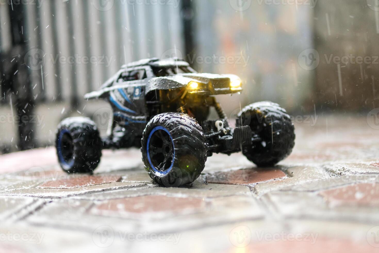 Toy car during outdoor rain with lights on. Remote Control Car being played in the yard during rain. Hobbies and Leisures. Toy Photography Concepts photo