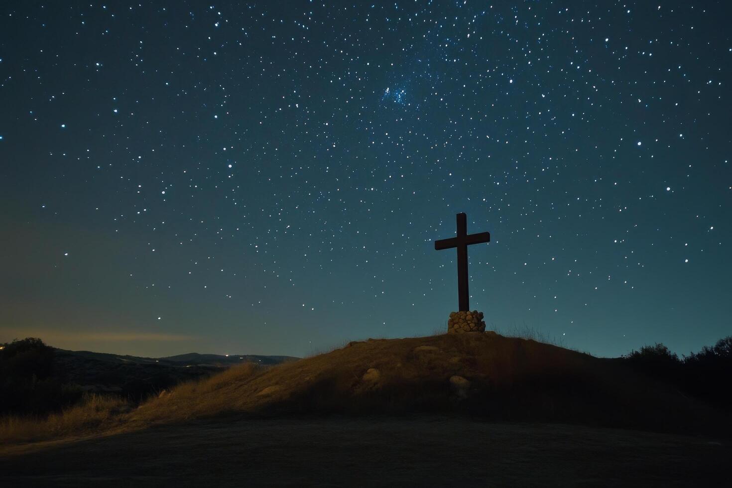 A cross stands on top of a hill with stars in the sky photo