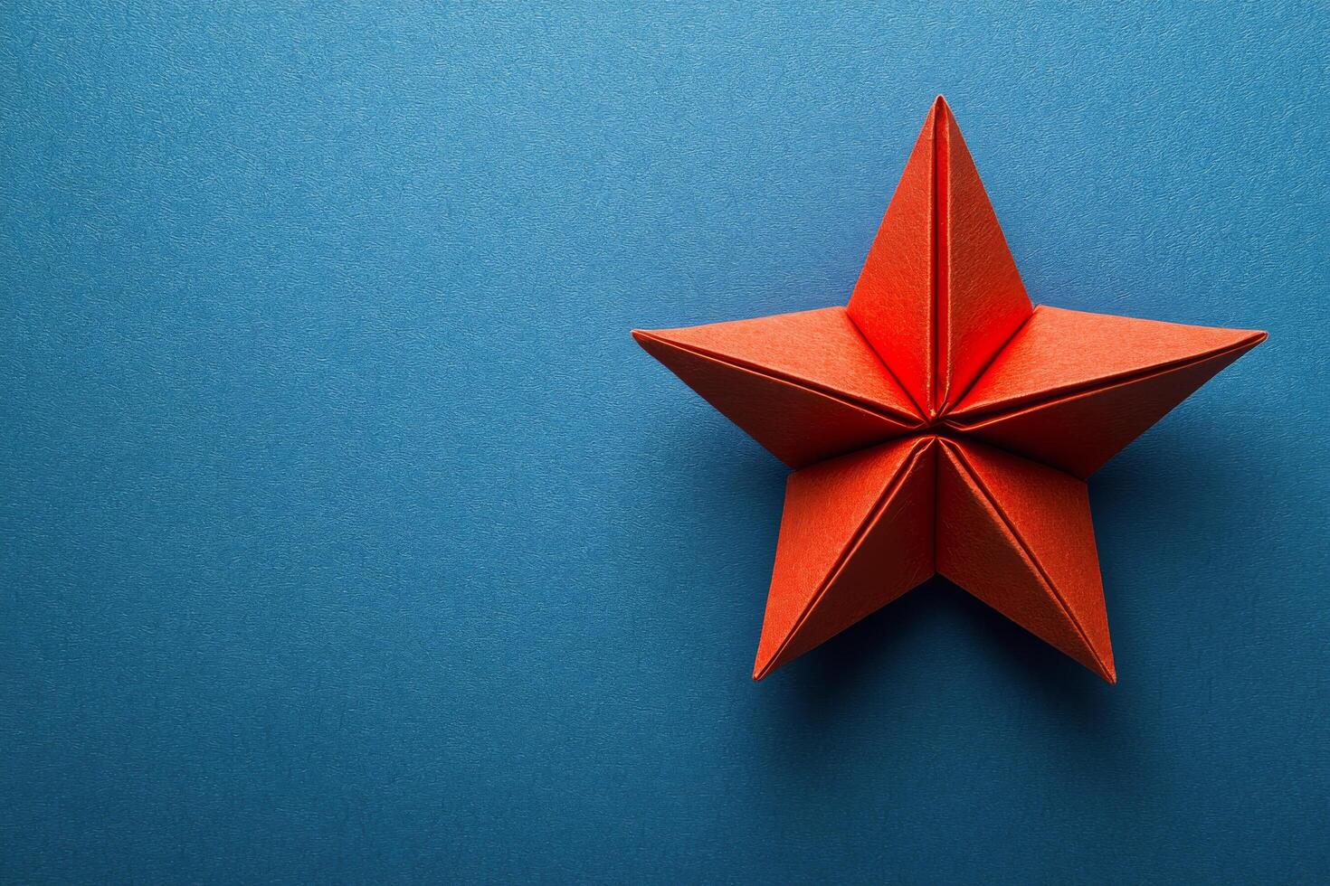 A red origami star on a blue background photo