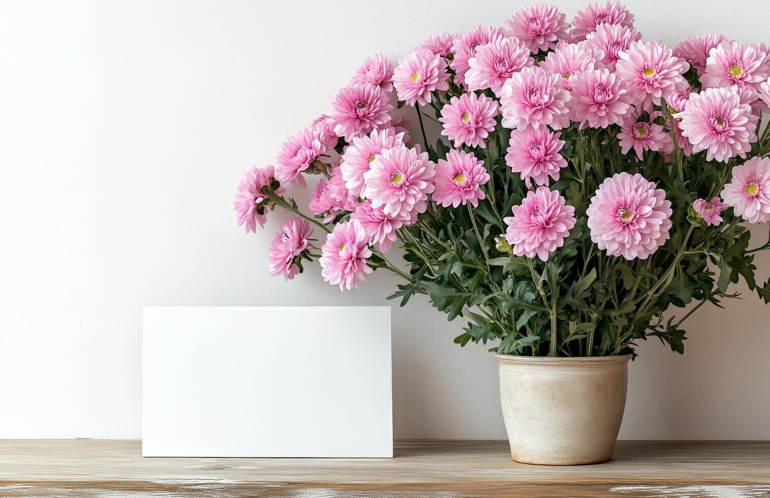 Pink flowers in a vase with blank card on wooden table photo