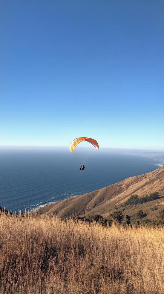 A person flying a paraglider over a grassy hill photo
