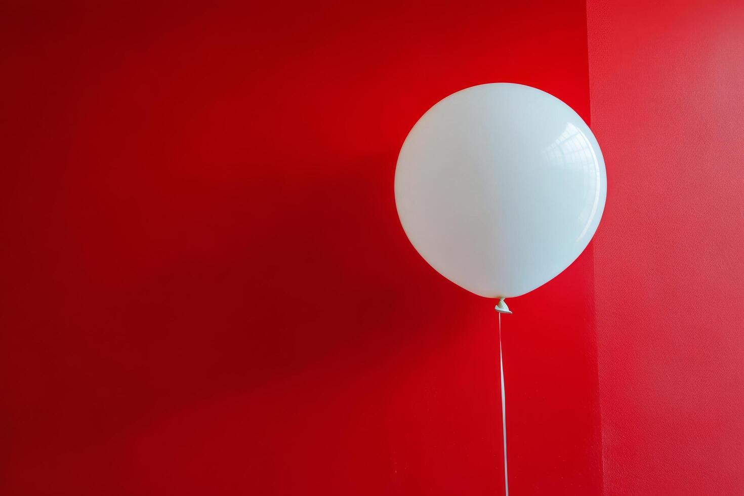 A white balloon is hanging from a red wall photo