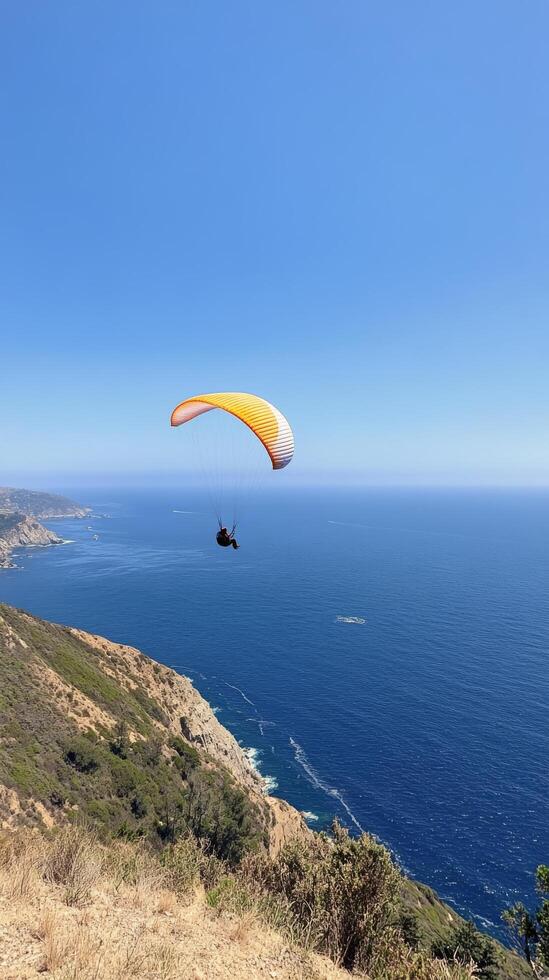 A paraglider flying over the ocean on a sunny day photo