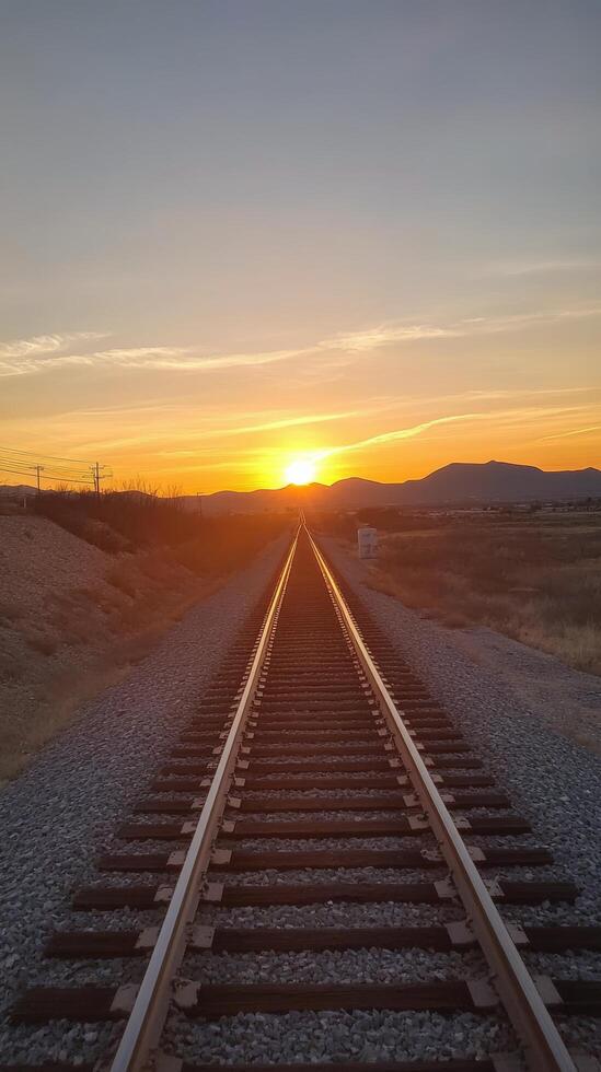 A railroad track is seen at sunset photo