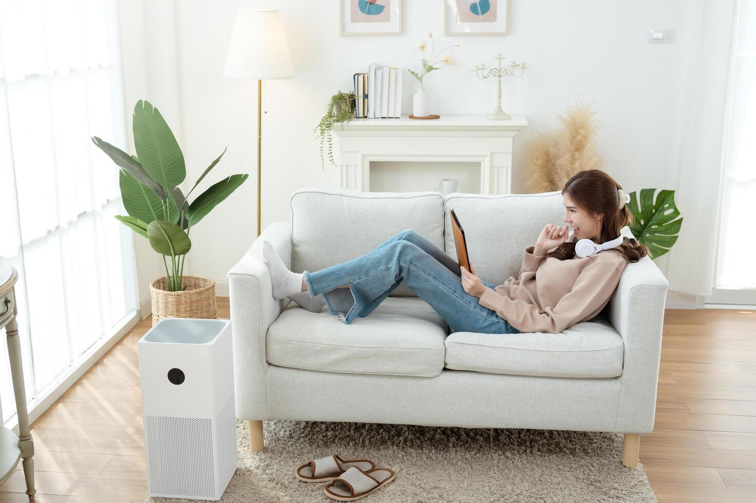 Young Woman Relaxing at Home on a Couch While Using a Tablet and Enjoying a Quiet Afternoon photo