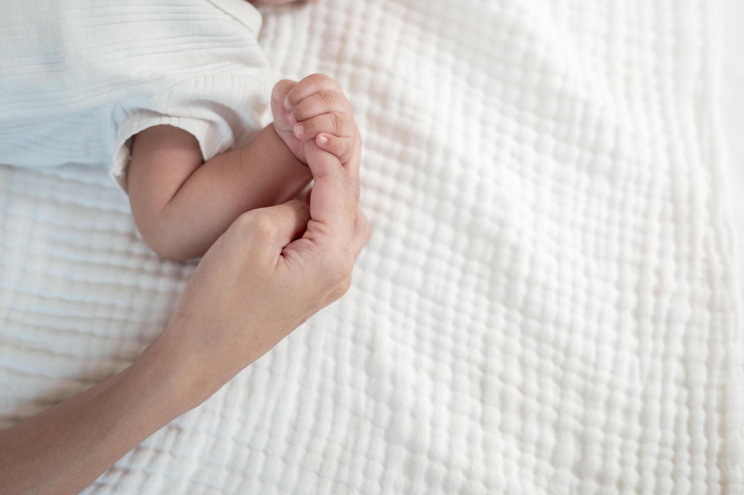 Tender Moment of Parent Holding Newborn's Hand on a Soft Blanket in a Cozy Setting photo