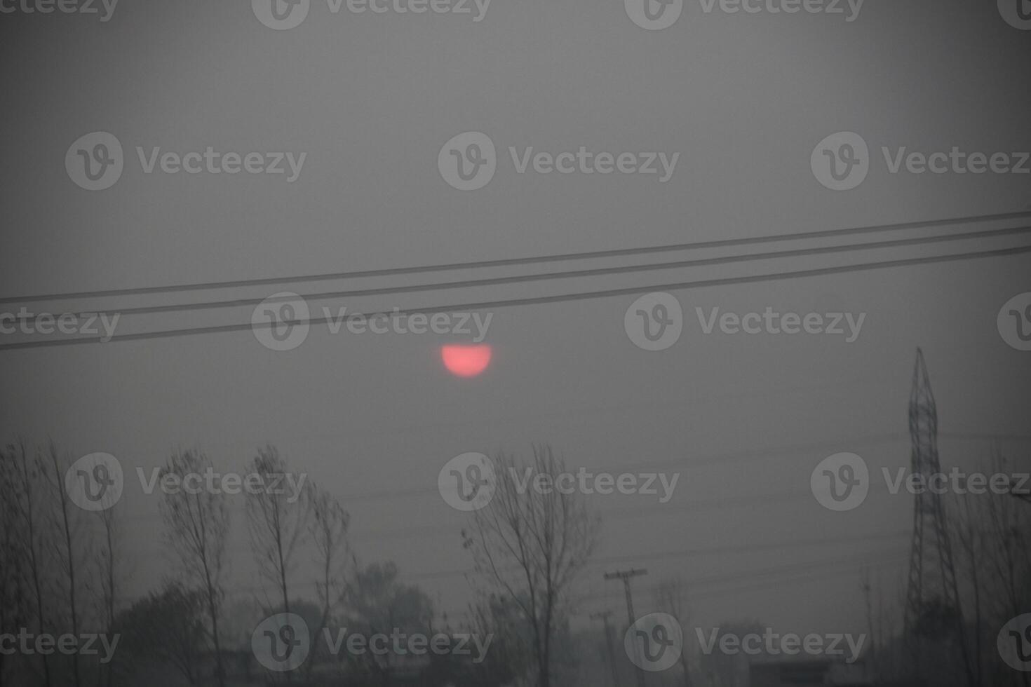 The sun is setting behind a power line photo
