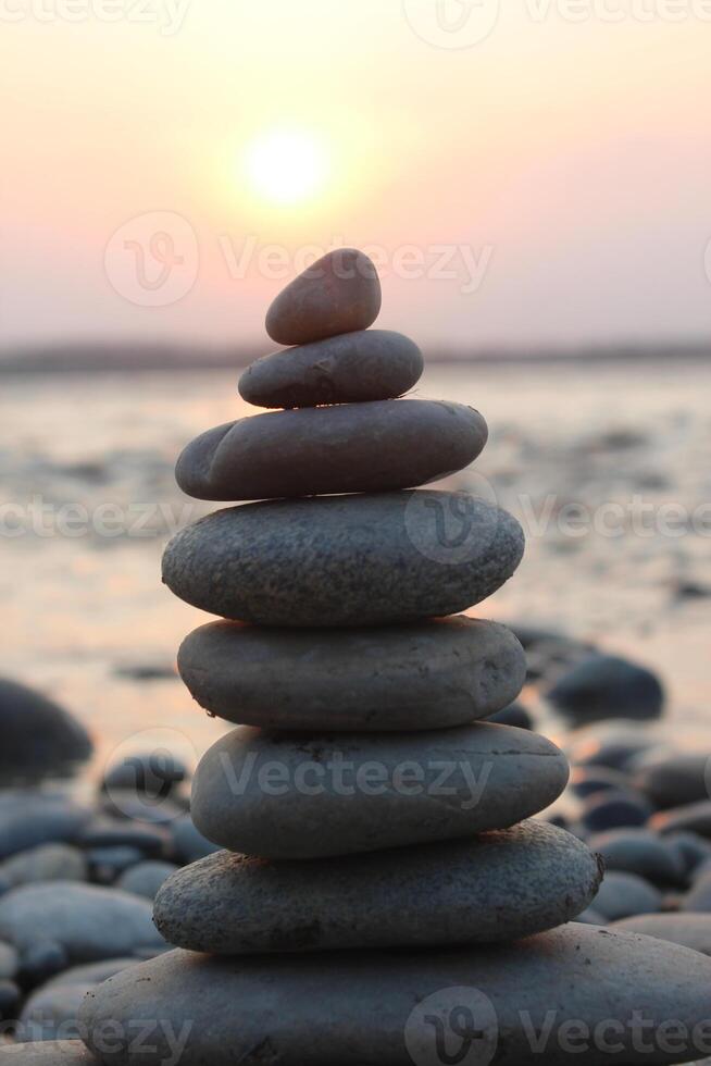 A stack of stones on the beach at sunset. photo