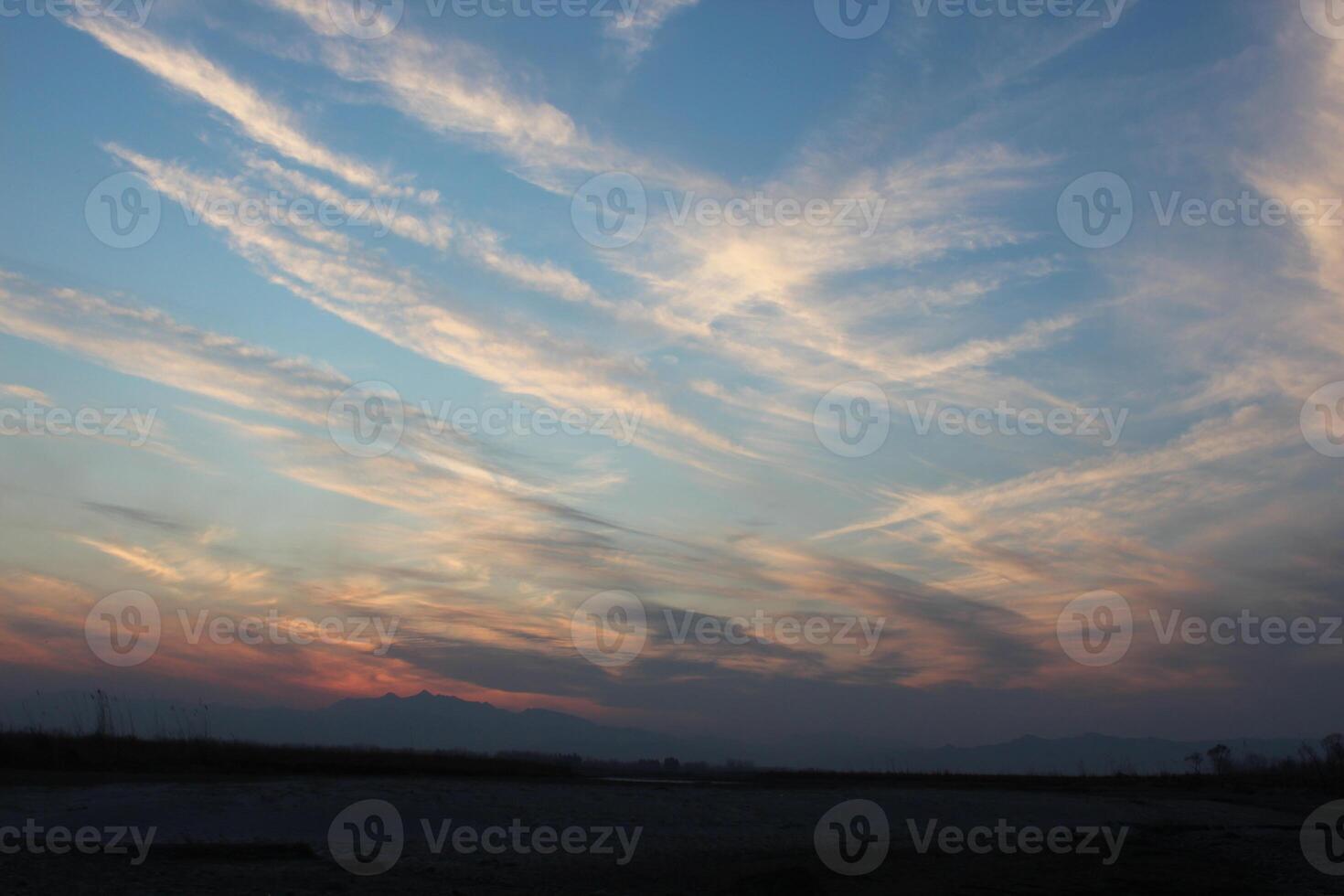 A plane flying over a field at sunset photo