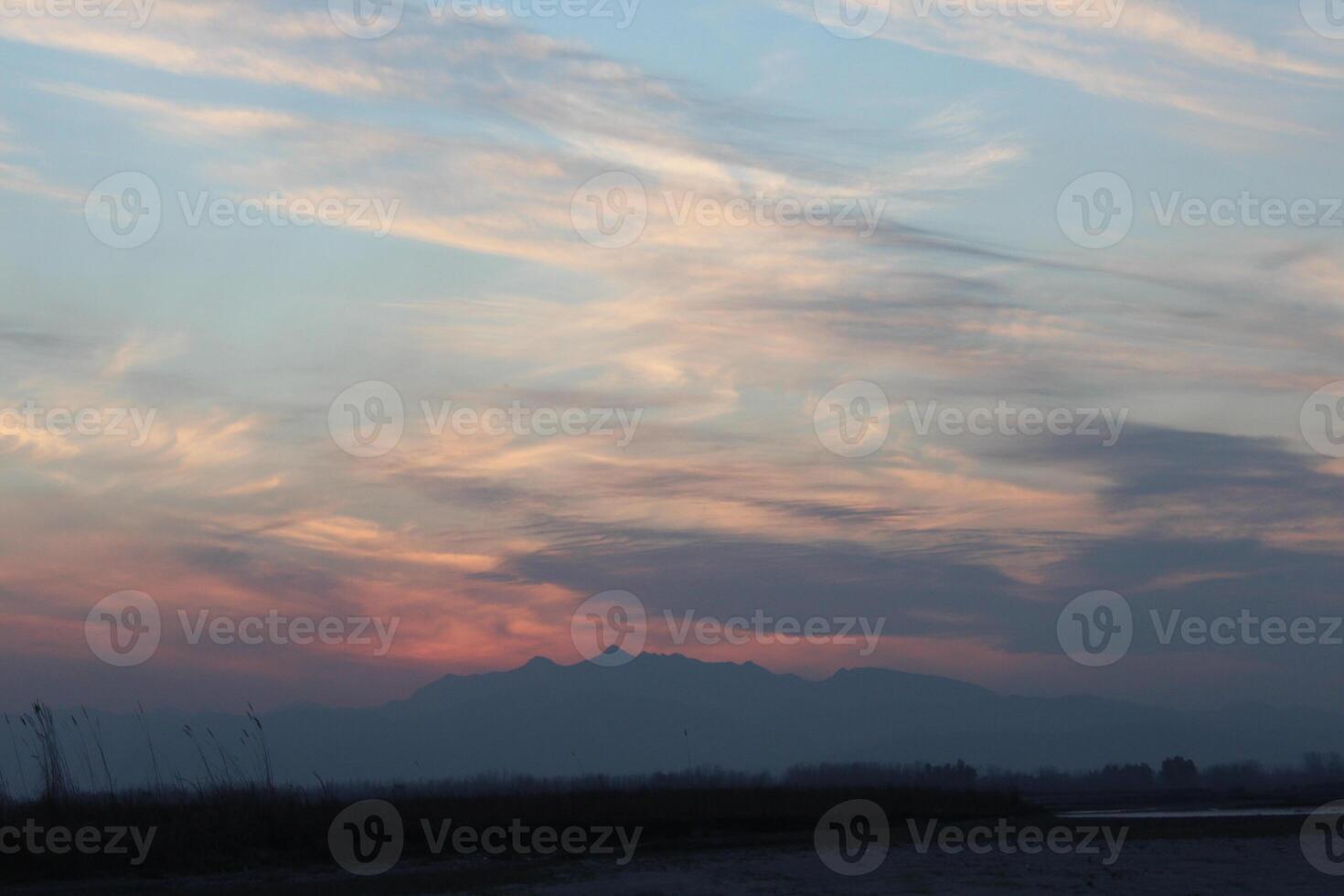 A plane flying over a field with mountains in the background photo