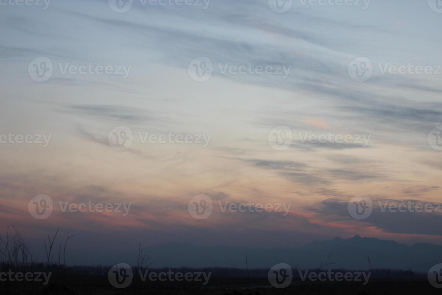A plane flying over a field at dusk photo